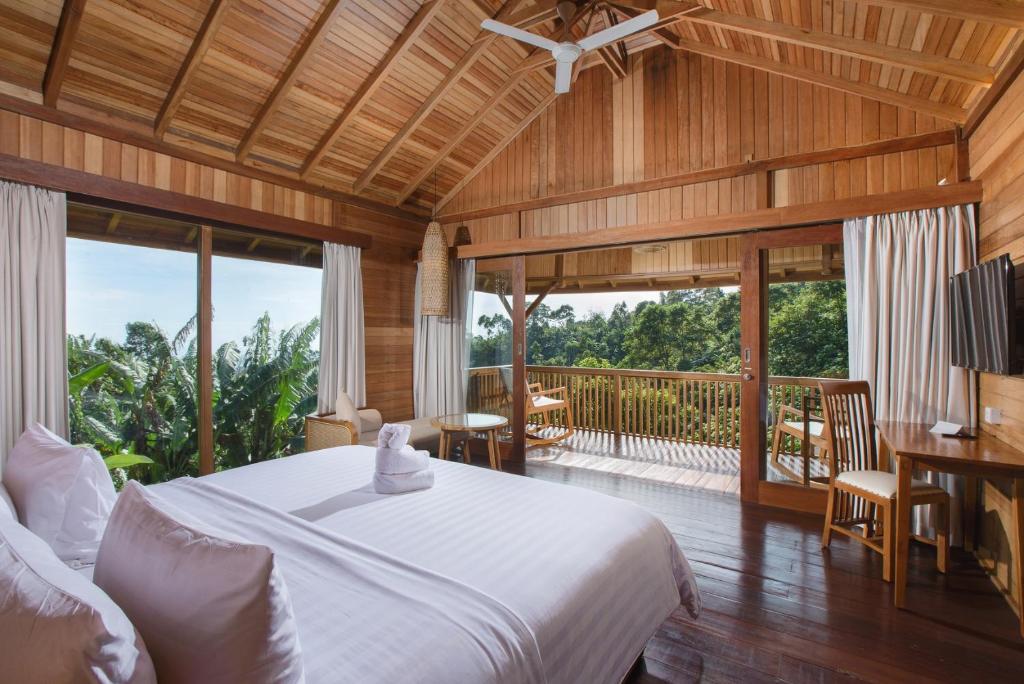 een slaapkamer met een groot bed en een balkon bij Giriwood Hotel & Villa in Bedugul