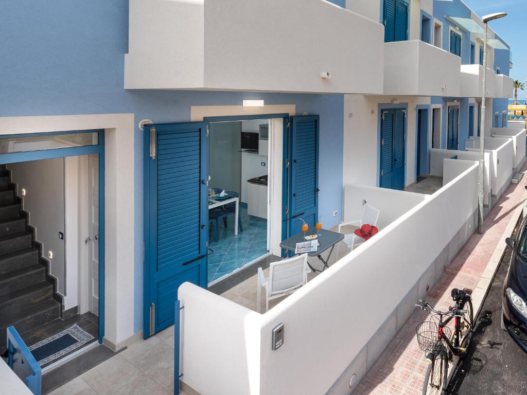 a building with blue doors and a balcony at IL FARO E LA LUNA Beach Apartments in San Vito lo Capo