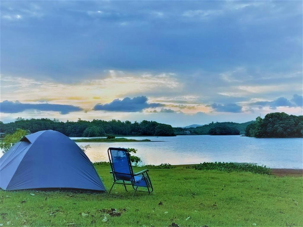 uma tenda azul e uma cadeira ao lado de um lago em Kaliraya Surf Kamp by Eco Hotel Laguna em Cavinti