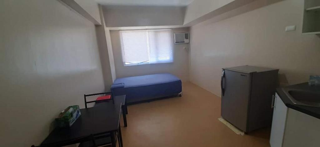 Habitación pequeña con cama azul y ventana en A’s Condo en Iloílo