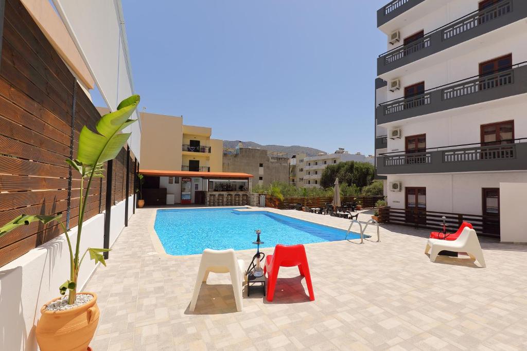 a large swimming pool with chairs next to a building at Antiko Apts & Studios in Hersonissos