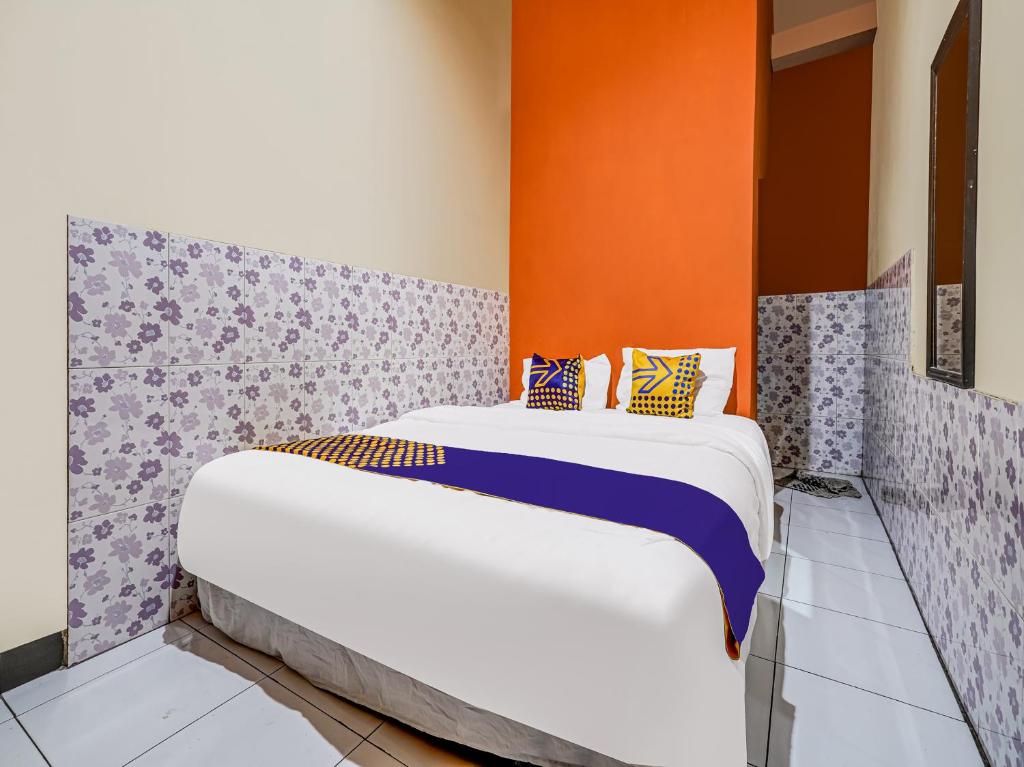 Ce lit se trouve dans un dortoir doté d'un mur orange. dans l'établissement SPOT ON 91186 Losmen Yanti, à Bandung