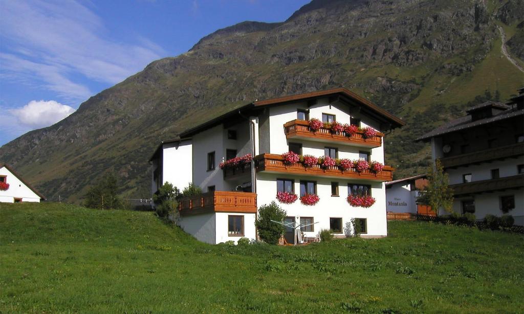 un edificio blanco con cajas de flores en una colina en Apart Christine - Silvrettacard-Sommer inklusive, en Galtür