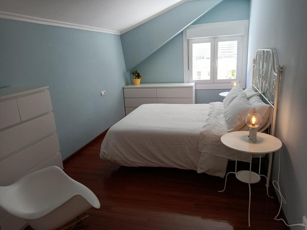 ein Schlafzimmer mit einem weißen Bett und einem Tisch mit einer Kerze in der Unterkunft Rodeira in Cangas