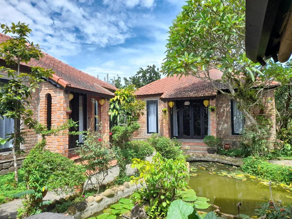 a brick house with a pond in front of it at Tam Tinh Vien Homestay in Hue