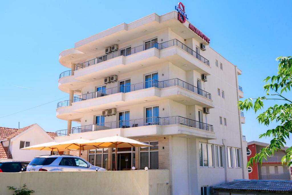 un grand bâtiment blanc avec des parasols devant lui dans l'établissement MS Hotel, à Dobra Voda