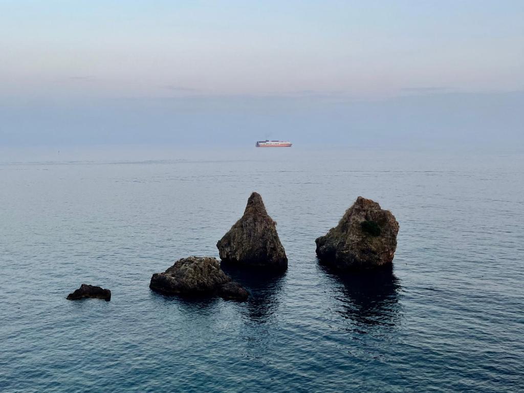 Trois rochers dans l'eau avec un navire à distance dans l'établissement Casa Titti, à Vietri