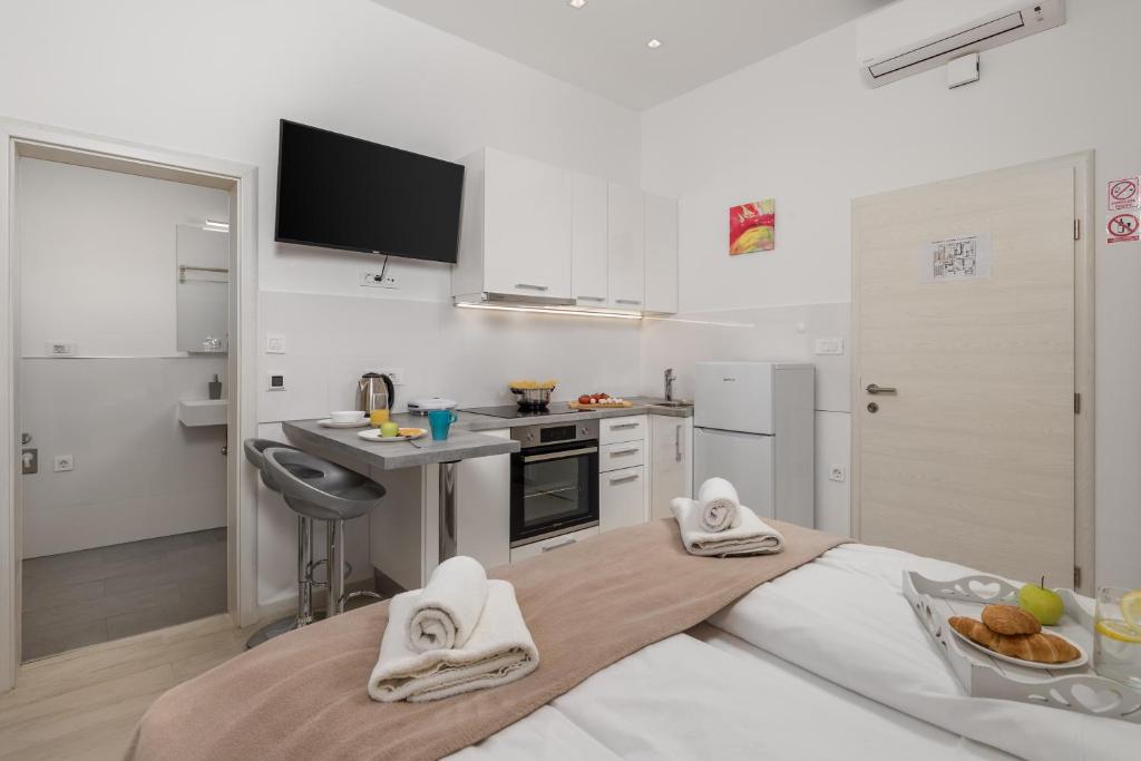 a white kitchen with a sink and a table with towels at Lux Apartments in Rijeka