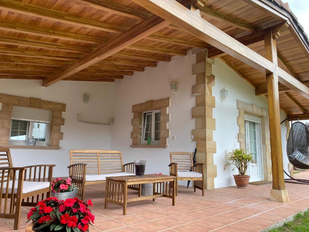 un patio con pérgola de madera, mesas y sillas en C02A01 Acogedora casa vacacional, en Los Corrales de Buelna