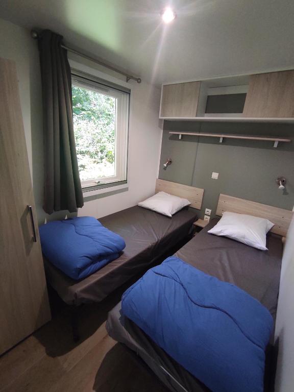 two beds in a small room with a window at Family&#39;s Camping Le Savoy in Challes-les-Eaux