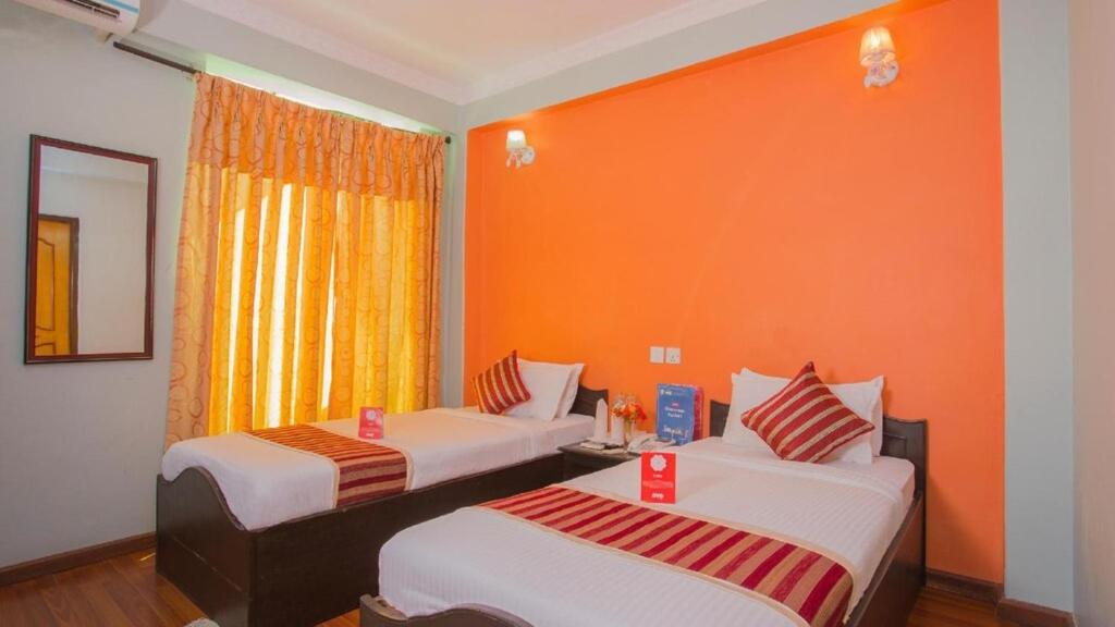 2 camas en una habitación con pared de color naranja en Dream Inn Pokhara, en Pokhara