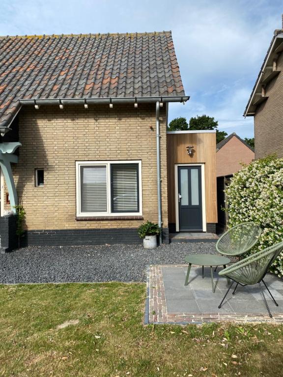 una casa con una mesa y un banco en el patio en ‘t Hoekje 49, en Biggekerke