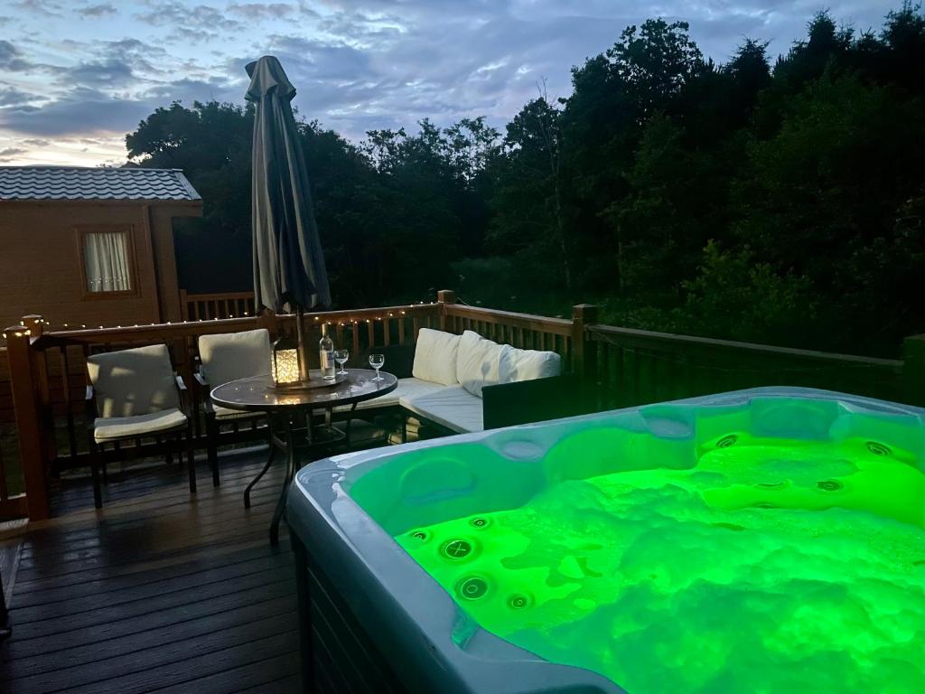 Felton的住宿－Carre Retreat with private hot tub，甲板上的热水浴池配有桌子和遮阳伞