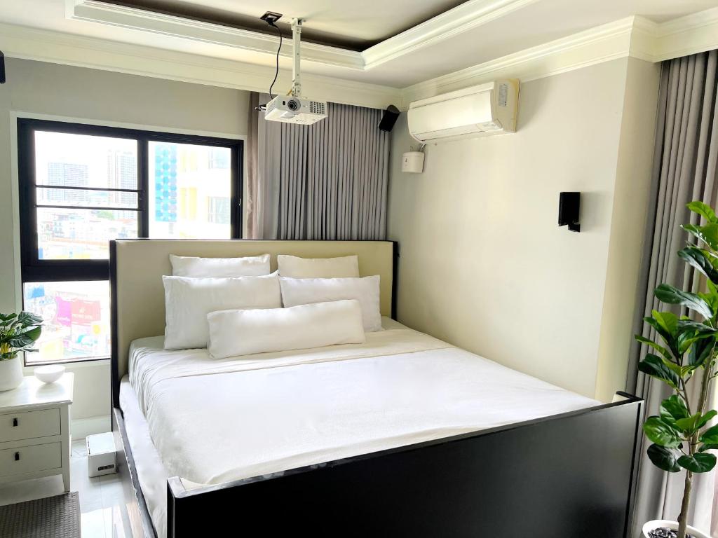 a bedroom with a bed with white sheets and pillows at Grand Diamond Condominium in Bangkok