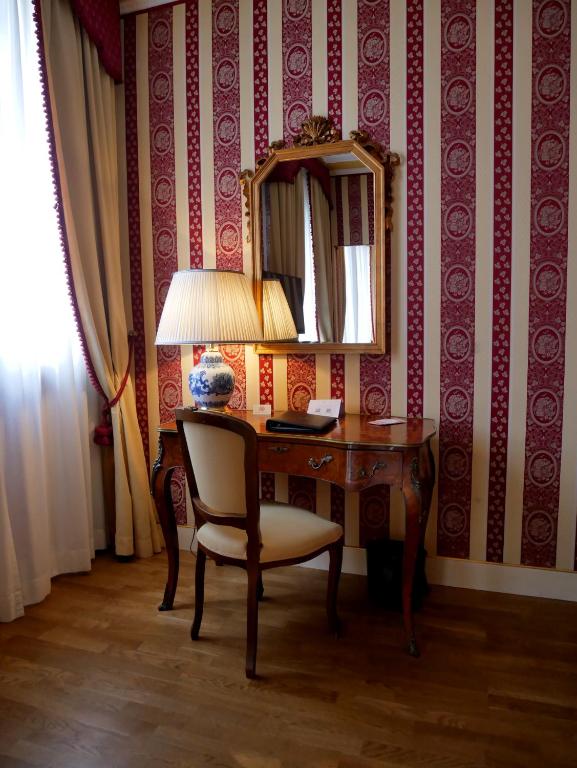a desk with a chair and a lamp and a mirror at Sina Palazzo Sant'Angelo in Venice