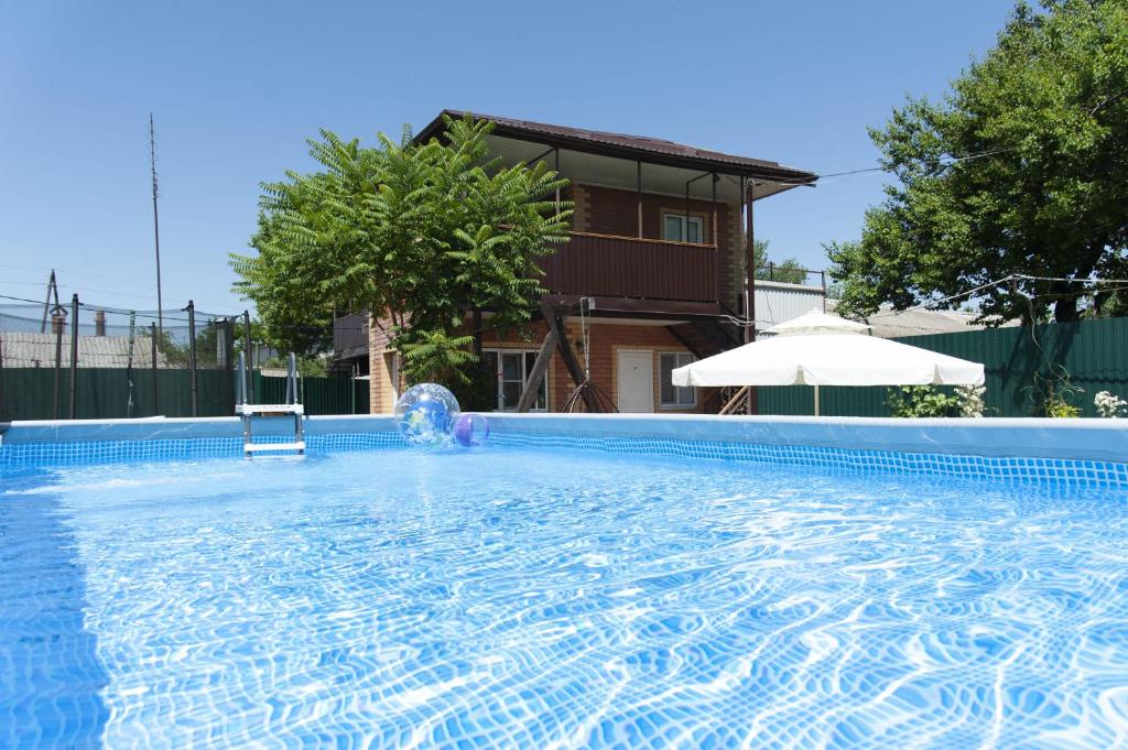 uma grande piscina com um macarrão de piscina em frente a uma casa em Guest House Apelsin em Yeysk