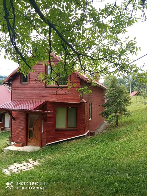 a small red house with a green yard at Котедж "Барвінок" in Verkhovyna