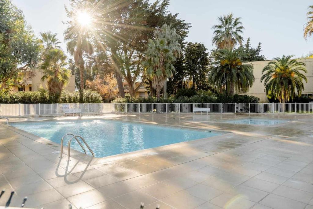 una piscina con palmeras en el fondo en Spacious apartment at a 5 min walk from the beach en Antibes
