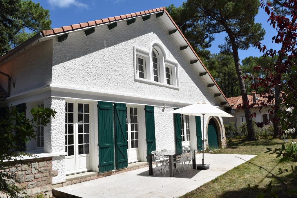 uma casa branca com portas verdes e um guarda-chuva em Maison basque dans les pins, au calme, 200m plage em La Baule