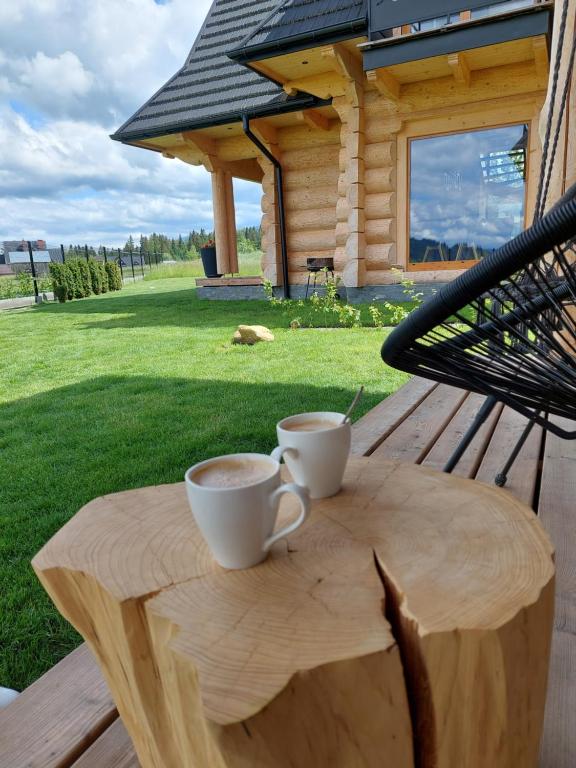 dos tazas de café en una mesa de madera frente a una cabaña en WIOSKA RUSIŃSKI, en Bukowina Tatrzańska
