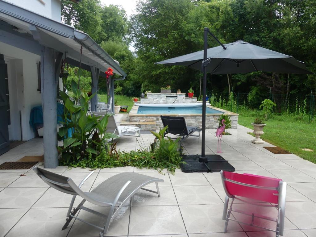 une terrasse avec des chaises et un parasol ainsi qu'une piscine dans l'établissement Toki Eder chez Marisol, piscine chauffée, décoration soignée et océan à 15 minutes entre Bayonne et Hossegor, à Saint-Martin-de-Seignanx