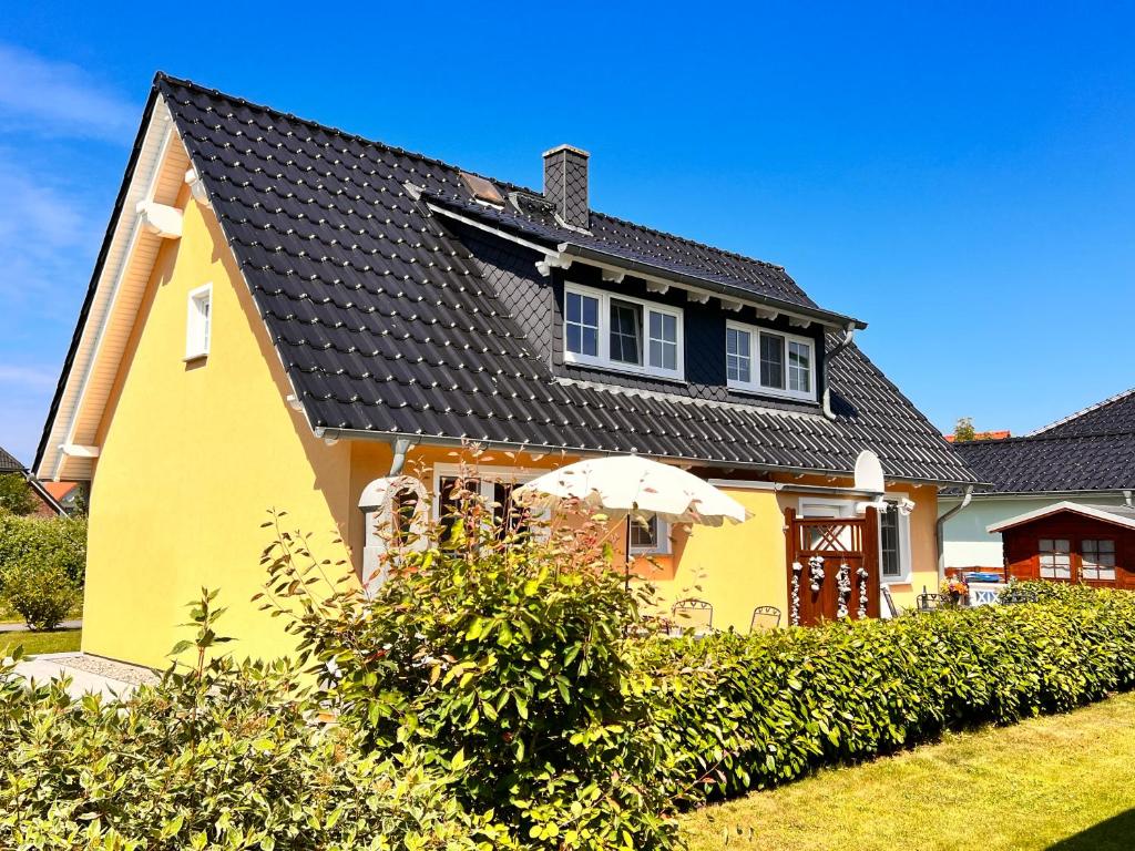 a yellow house with a black roof at Ferienhaus Anna - rechte Seite in Dranske