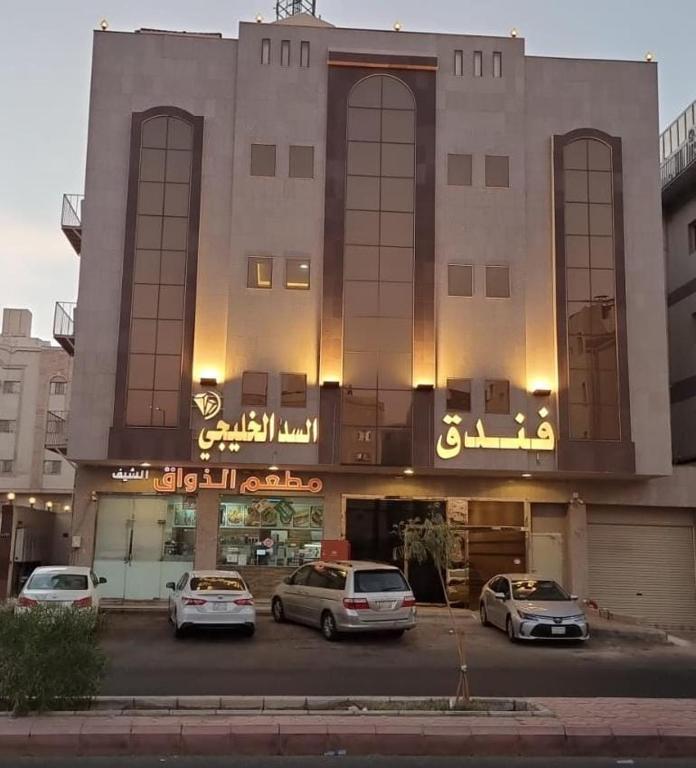 un edificio con coches estacionados frente a él en فندق السد الخليجى en Sīdī Ḩamzah