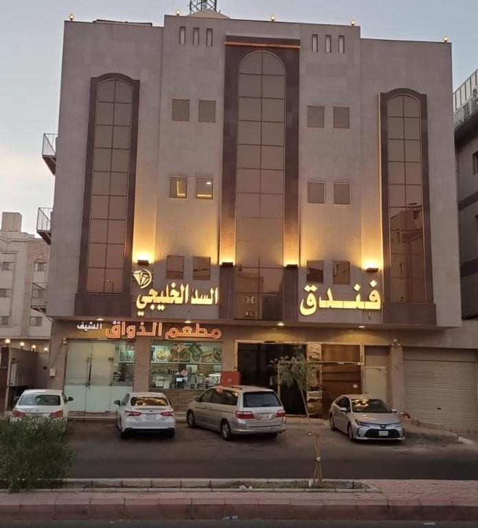 a building with cars parked in front of it at فندق السد الخليجى in Sīdī Ḩamzah