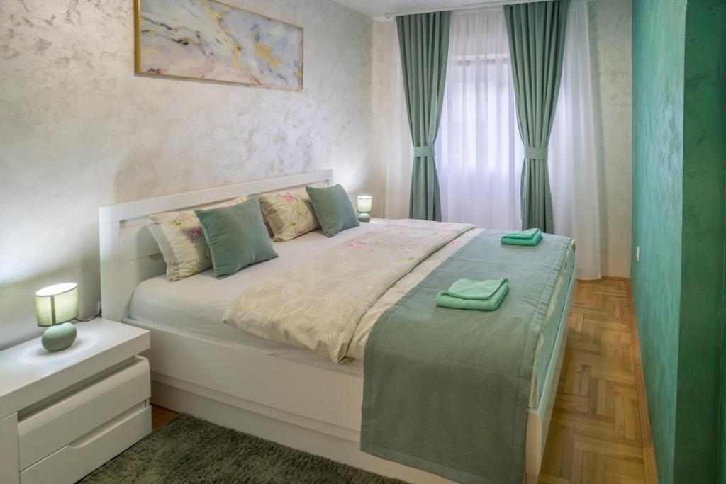 - une chambre avec un grand lit blanc et des rideaux verts dans l'établissement Lux Deluxe Apartment, à Žabljak