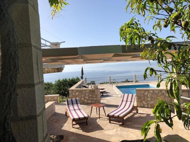 two chairs and a table next to a swimming pool at kamena kuća kanava in Selca