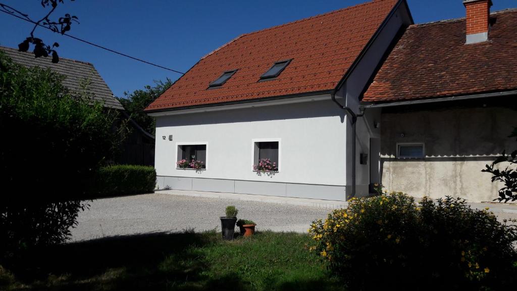 a white building with a red roof and two windows at Apartma Sterle in Stari Trg pri Ložu