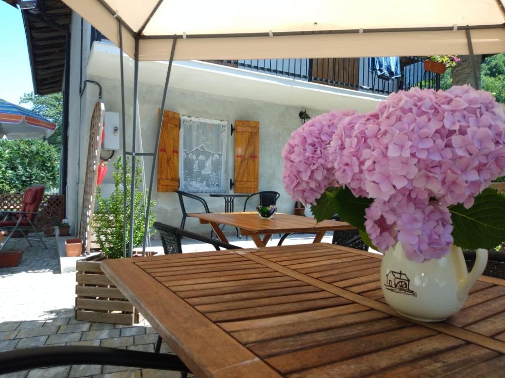 een vaas met roze bloemen op een houten tafel bij Il Ciliegio di Lurisia in Lurisia