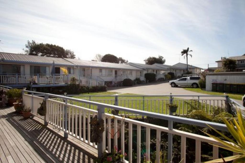 una casa con una valla blanca y un aparcamiento en Flats Elite Bermagui, en Bermagui