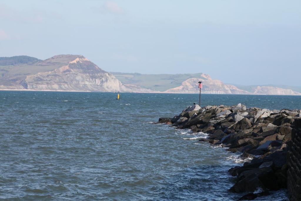 a group of rocks in the water with mountains in the background at Fernhill Hotel in Lyme Regis
