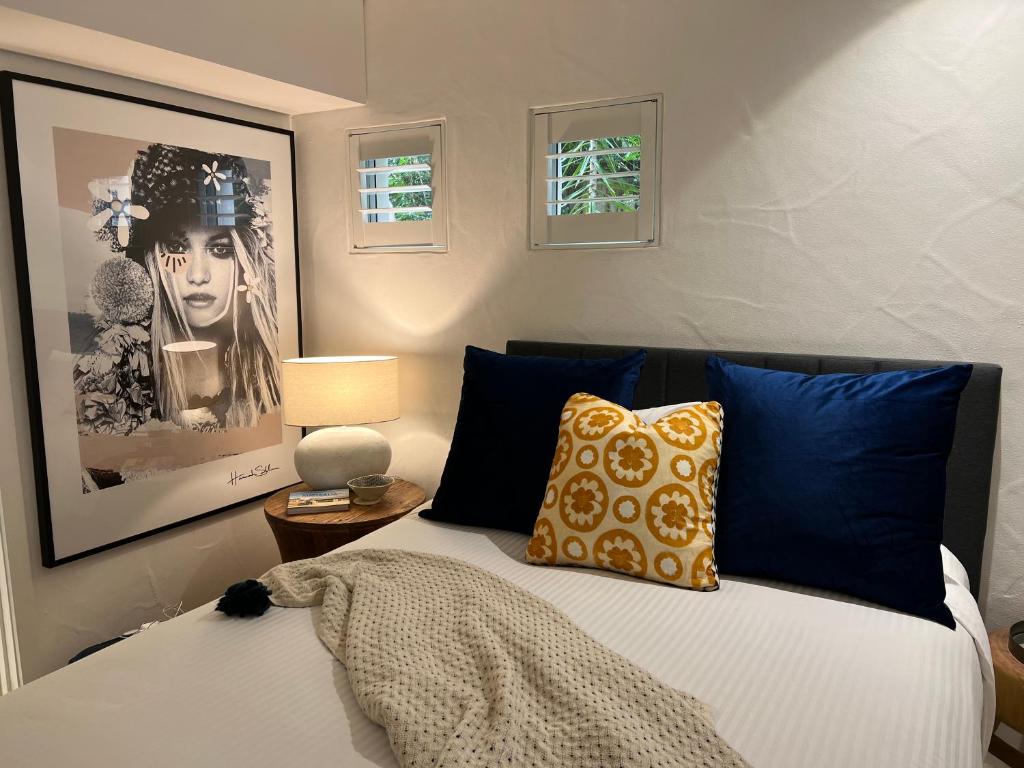 Carramah Noosa Heads apartment في نوسا هيدز: غرفة نوم بسرير مع وسائد زرقاء وصفراء