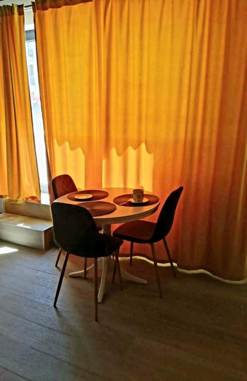 ein Tisch und Stühle in einem Zimmer mit einem orangefarbenen Vorhang in der Unterkunft Nico Apartment in Mamaia Nord – Năvodari