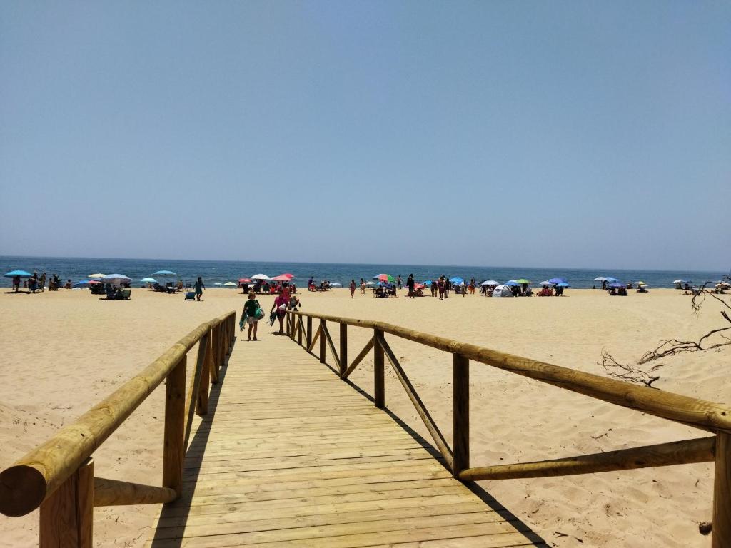 eine hölzerne Promenade am Strand mit Leuten darauf in der Unterkunft Sol y Mar in Isla Cristina
