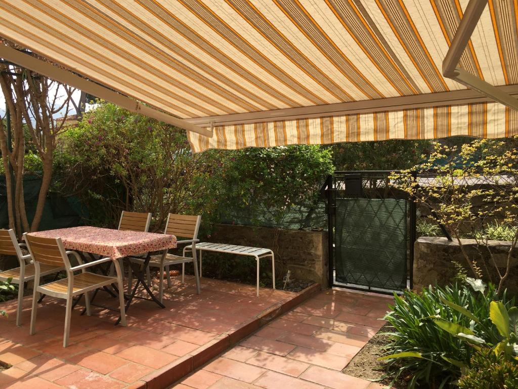 un patio avec une table et des chaises sous une pergola dans l'établissement BEL APPARTEMENT 4Pers RDC/parking/terrasse/ jardin, à Collioure