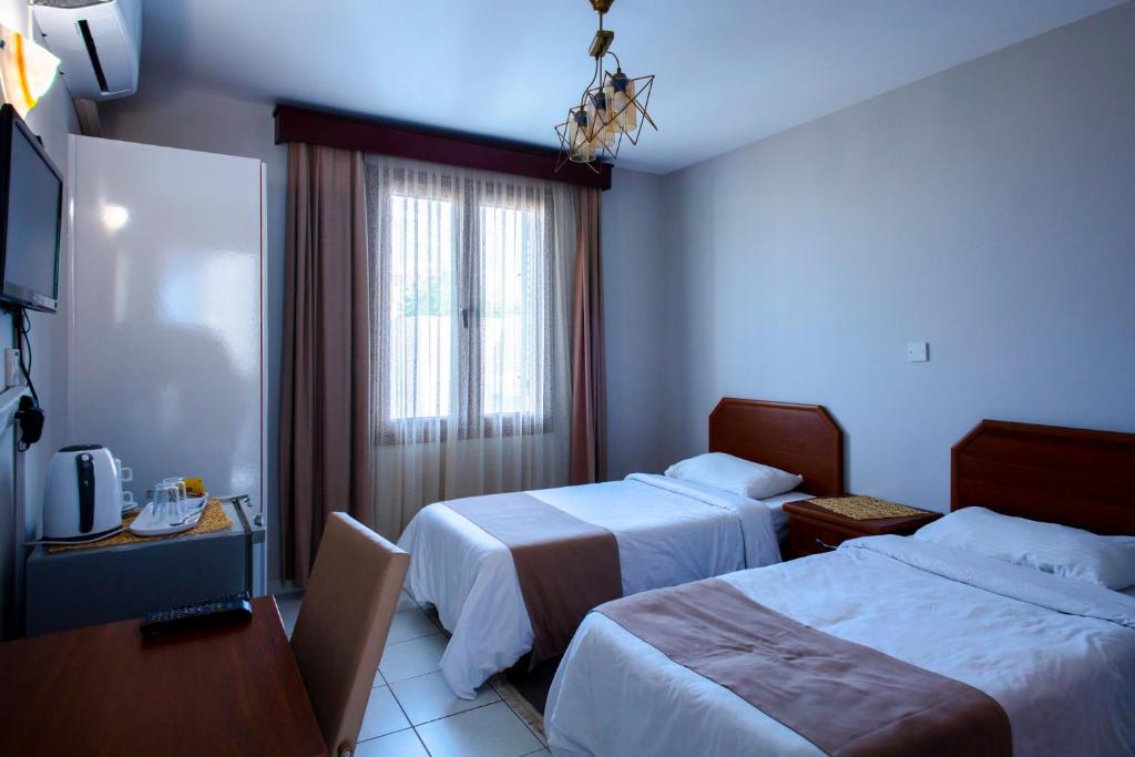 a hotel room with two beds and a television at Homelike Guest house in Kyrenia
