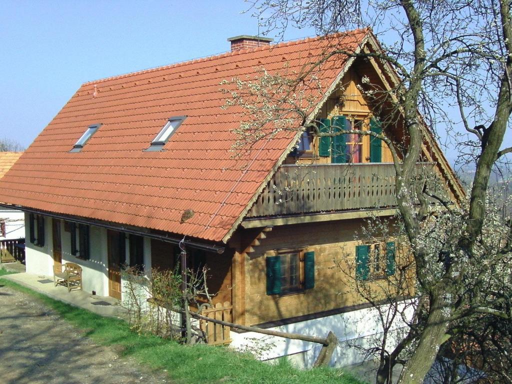 ein Haus mit einem orangenen Dach und einem Baum in der Unterkunft Biohof/Gästezimmer Adam in Großklein