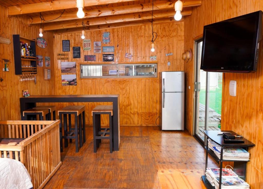 uma cozinha com um bar e uma televisão em uma sala em Surf and Stay Chile em Navidad