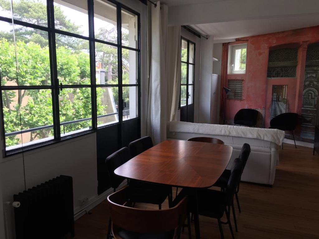 a table and chairs in a room with windows at Numéro 5 in Boulogne-Billancourt