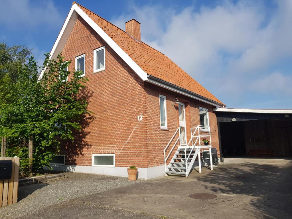 un edificio de ladrillo con una escalera en su lateral en Hus til stor familie en Bredebro