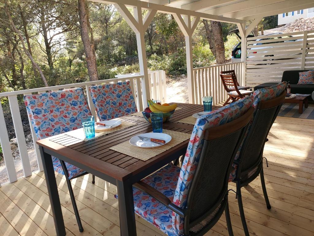 a wooden table and chairs on a deck at Philomena Mobile home Camping Pasman in Pašman