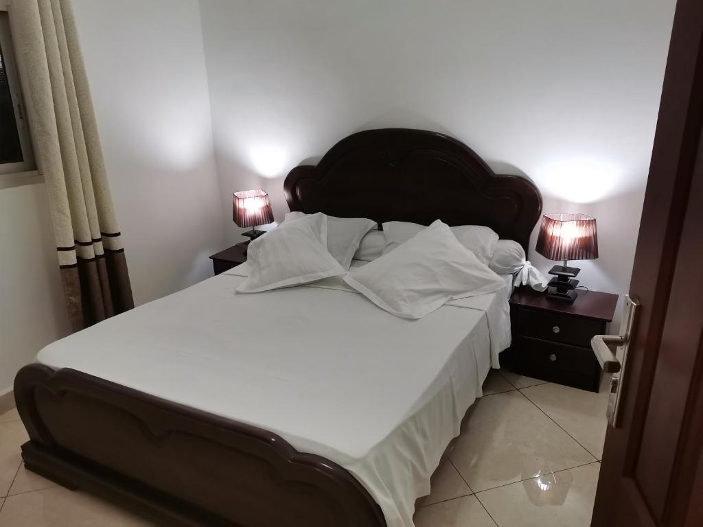 a bedroom with a large bed with white sheets and pillows at Résidence Hôtelière MB-4E in Douala