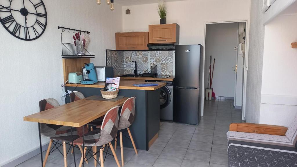 eine Küche mit einem Tisch und einem Kühlschrank in der Unterkunft F2 saint Cyprien Plage in Saint-Cyprien