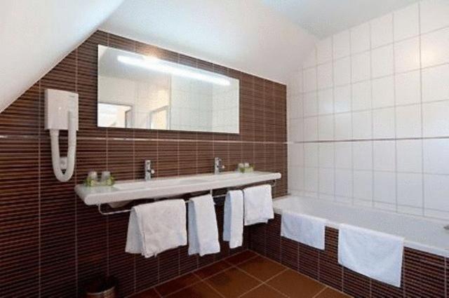 a bathroom with a tub and a sink and a mirror at Hostellerie St Vincent in Nuits-Saint-Georges