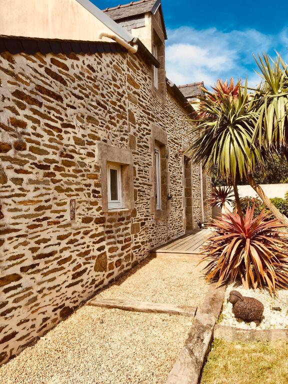 - un bâtiment en pierre avec un palmier à côté dans l'établissement TY JACQ, à Tréguennec
