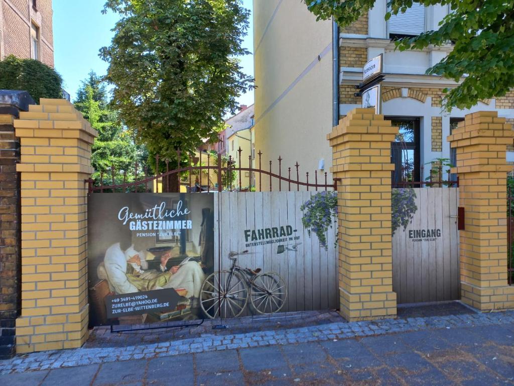 a fence with a poster on it next to a building at Pension Zur Elbe in Lutherstadt Wittenberg