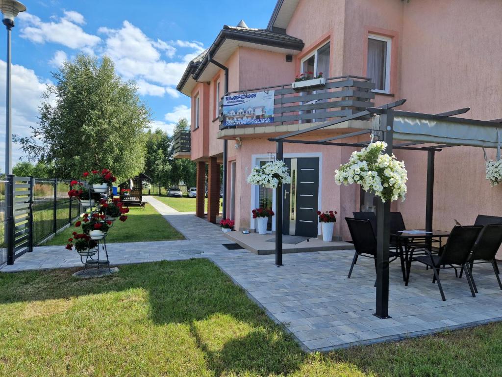 a patio with chairs and a table in front of a building at Dom Wypoczynkowy LAGUNA Gąski in Gąski